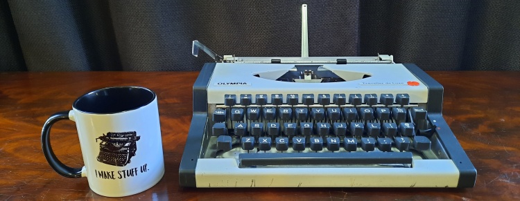 Typewriter, front view, with mug for scale. The typewriter is shorter than the mug.