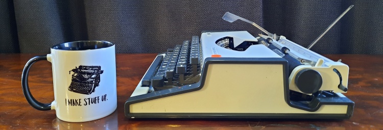 Side view of typewriter, with mug for scale. 